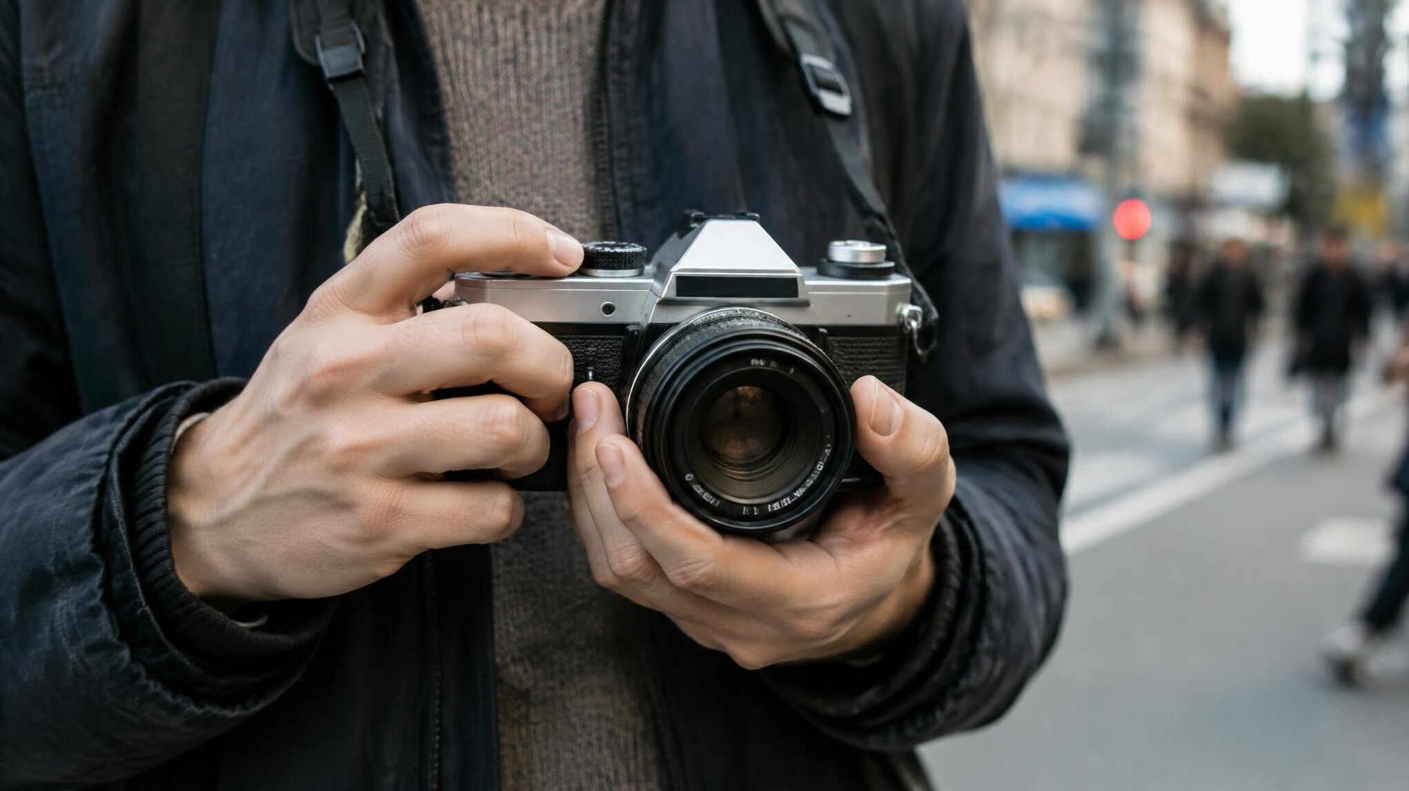 Close up of hands holding a film camera on a city street