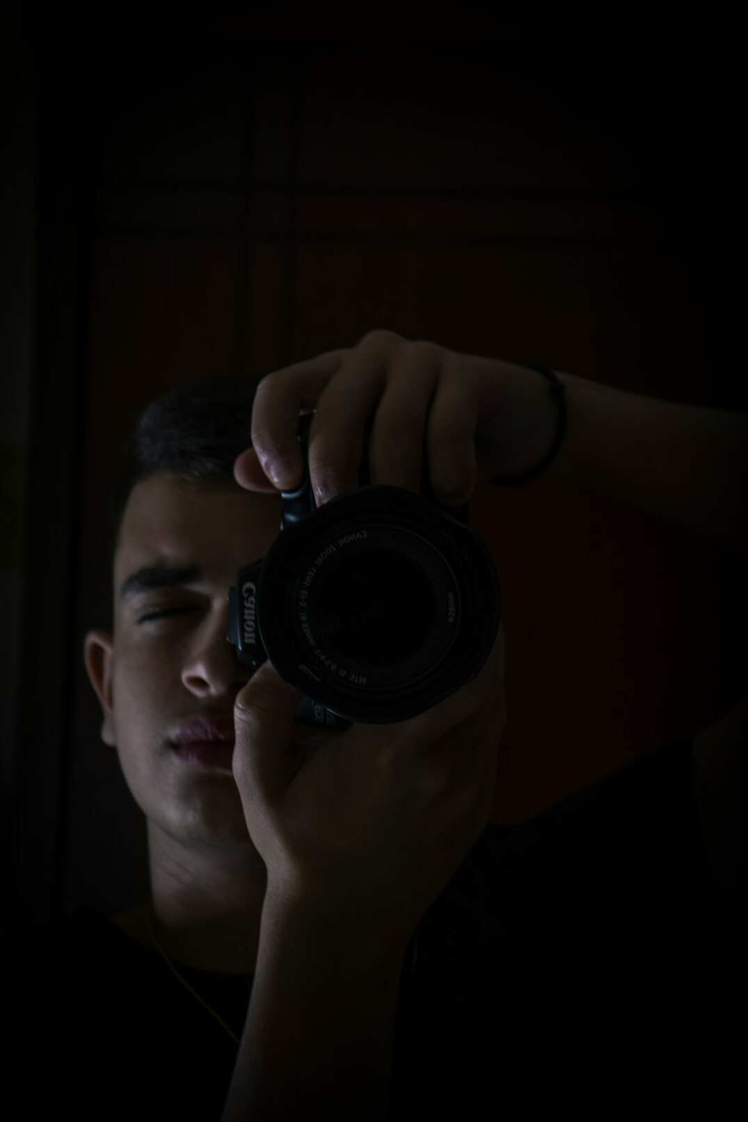 Studio portrait of a Latino male photographer with a camera around his neck